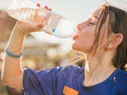 An image representing a person drinking water under the sun, symbolizing staying hydrated during hot weather